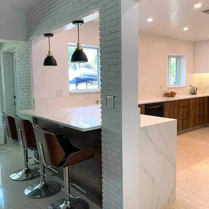 Modern marble island kitchen with green brick accent wall