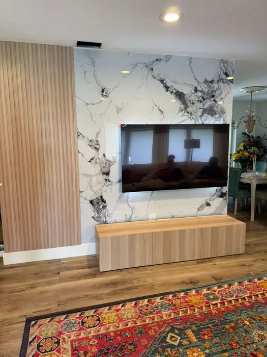 Modern living room with marble accent wall, wood-grain wall paneling, recessed lighting, floating media console with wall-mounted TV, and hardwood flooring